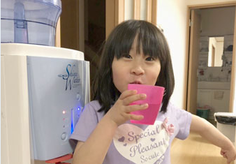 シャインウォーターの水を飲んで笑顔の子供